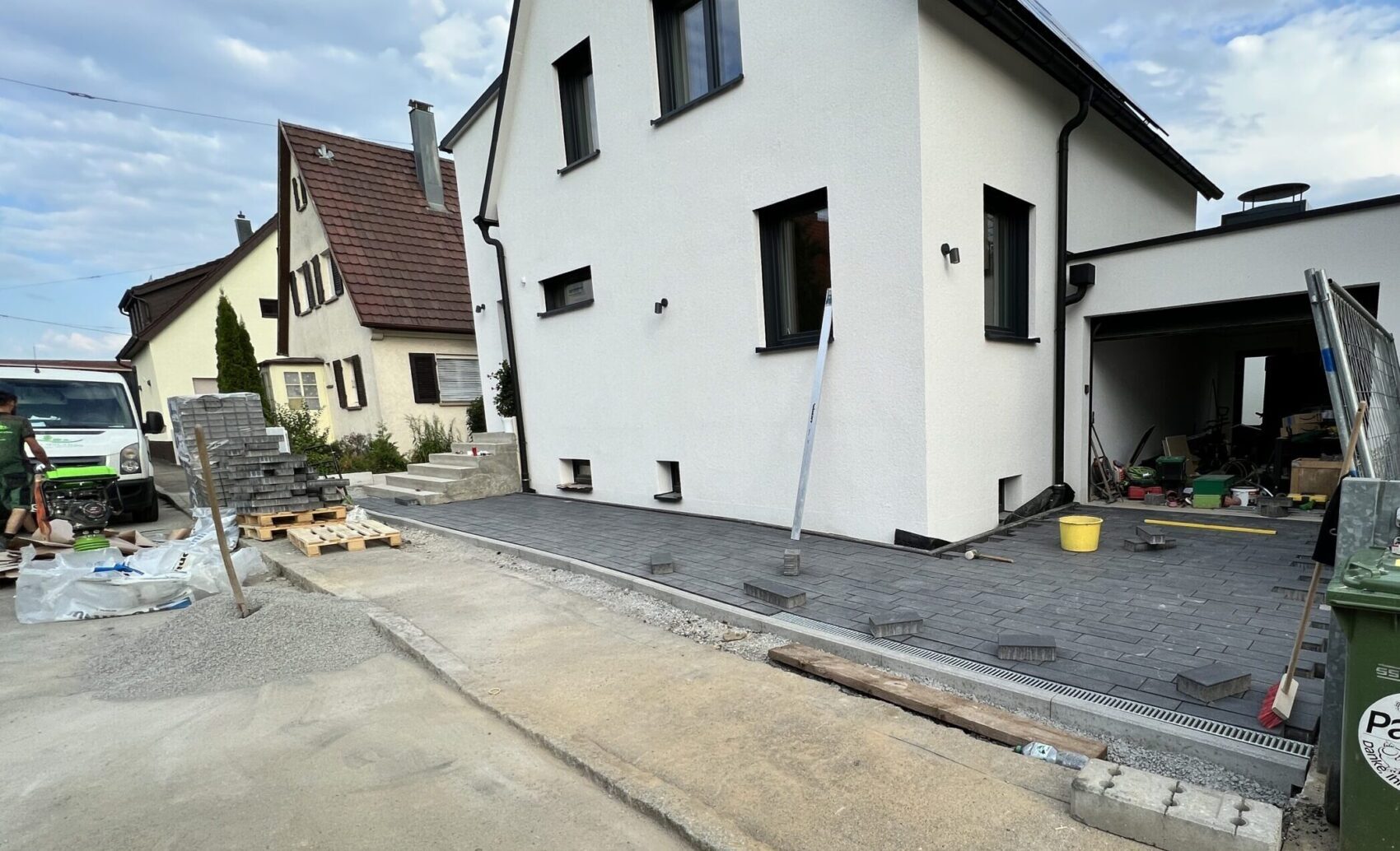 Neu gepflasterte Einfahrt und Hauszugang an einem modernen Wohnhaus während der Außenanlagenarbeiten.