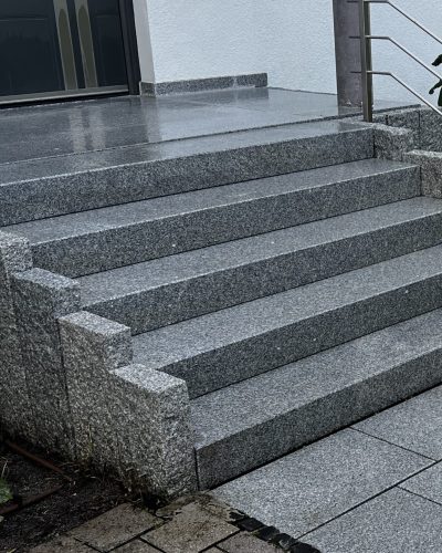 Moderne Granittreppe im Eingangsbereich mit Natursteinplatten und Edelstahlgeländer durch professionellen Galabau