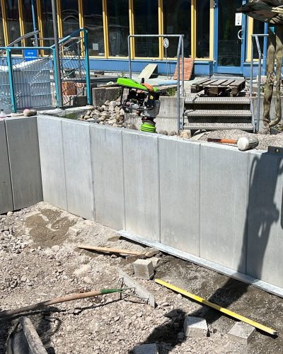 Mauerscheiben werden mit einem Bagger für eine Hangbefestigung von STROHGÄU GaLaBau im Raum Stuttgart verbaut.
