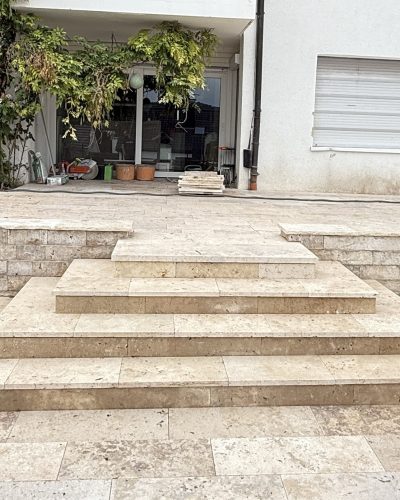 Naturstein-Terrasse mit breiter Treppenanlage und Stützmauer vor Wohnhaus durch professionellen Galabau