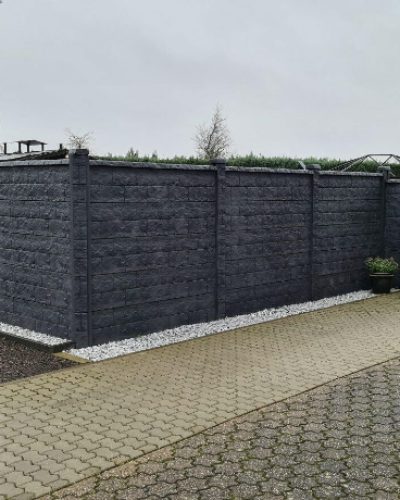 Anthrazitfarbener Sichtschutzzaun mit Gartentor und Kiesstreifen als moderne Grundstücksbegrenzung durch Galabau